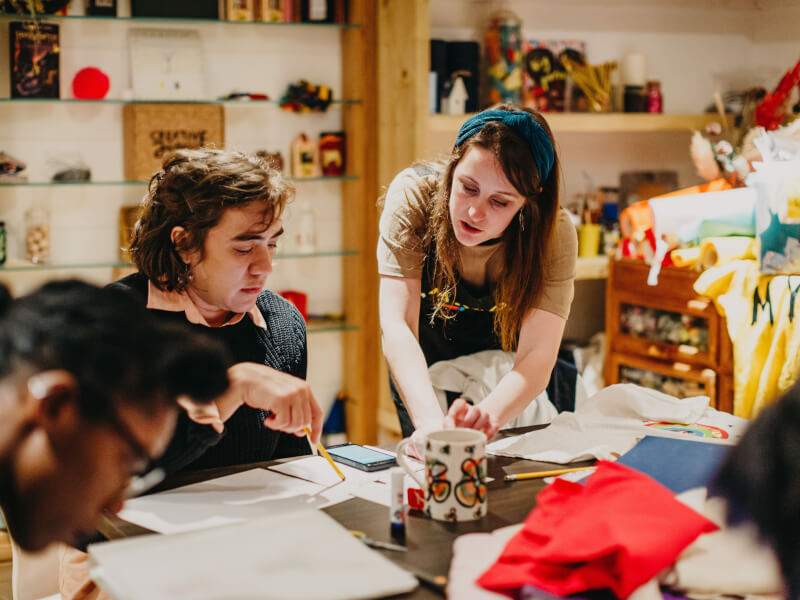 A teacher helping her students at a sewing class